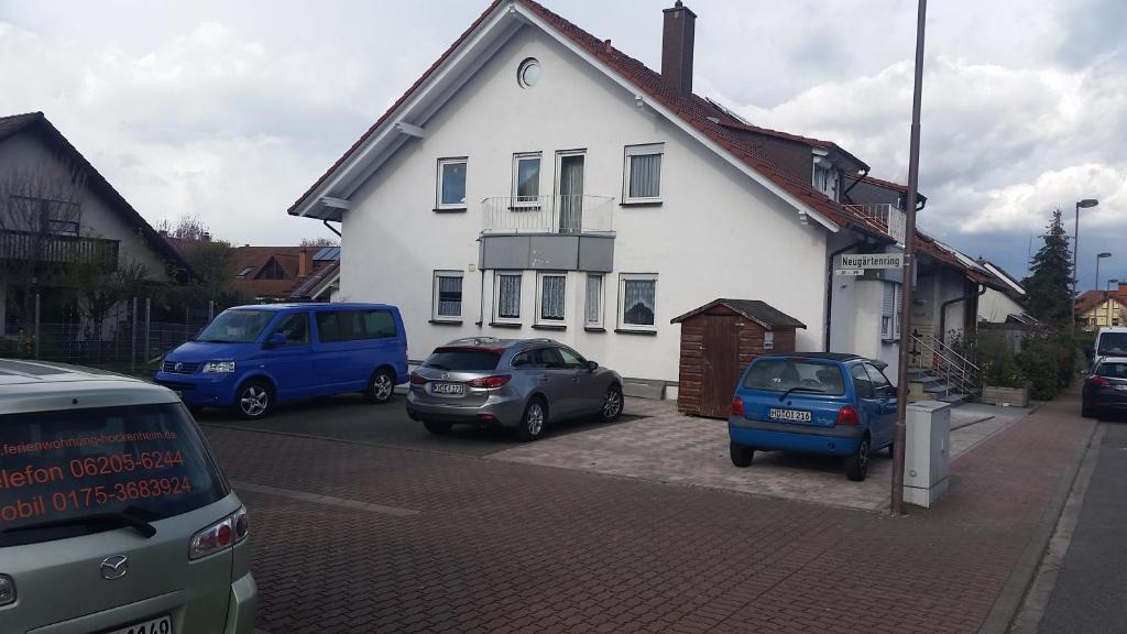 a white house with cars parked in a parking lot at Ferienwohnung Sandra Hockenheim in Hockenheim