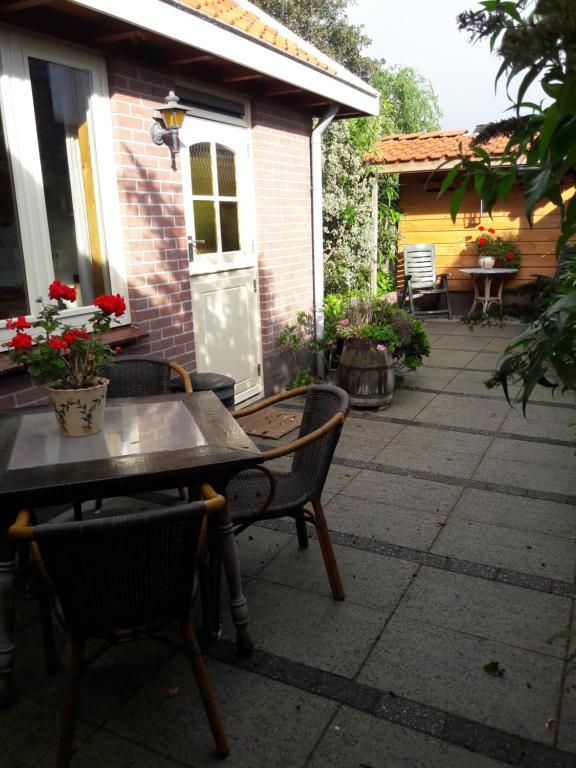 a patio with a table and chairs and a house at De Stern en de Beuk in Groet