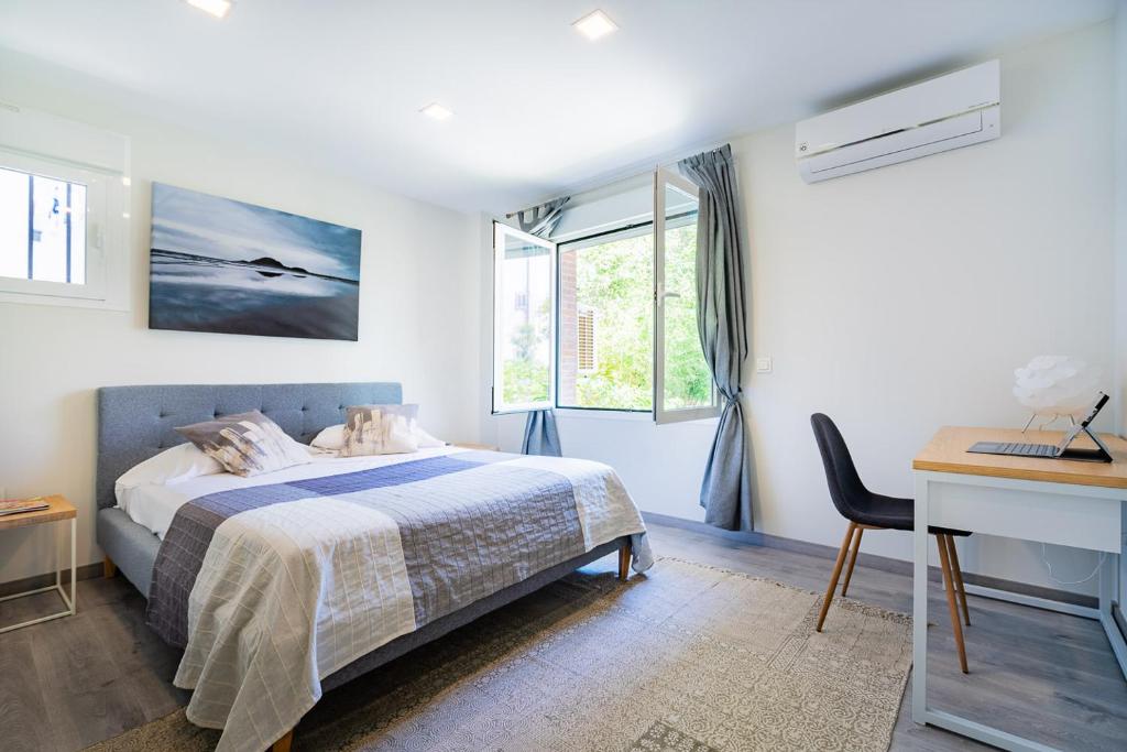 Schlafzimmer mit einem Bett, einem Schreibtisch und einem Fenster in der Unterkunft Exclusive quietness in the heart of Madrid with Public Parking, Breakfast, 2 bathrooms in Madrid