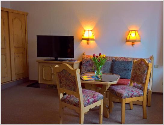 een woonkamer met een tafel, een bank en een televisie bij Gasthof-Pension Rotes Haus in Kurort Oberwiesenthal