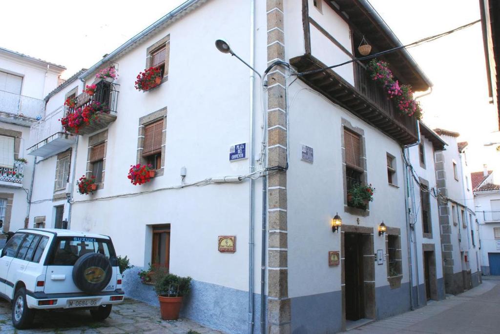 un bâtiment blanc avec des boîtes de fleurs et une voiture garée à côté. dans l'établissement Casa Rural Beit Shalom, à Hervás