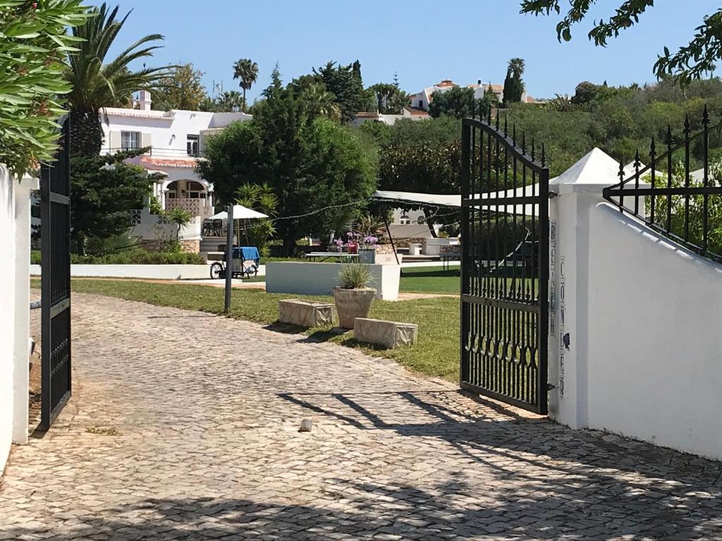 a gate leading to a park with trees and houses at CASA BEACHCOMBER Le jardin des Arts in Lagos