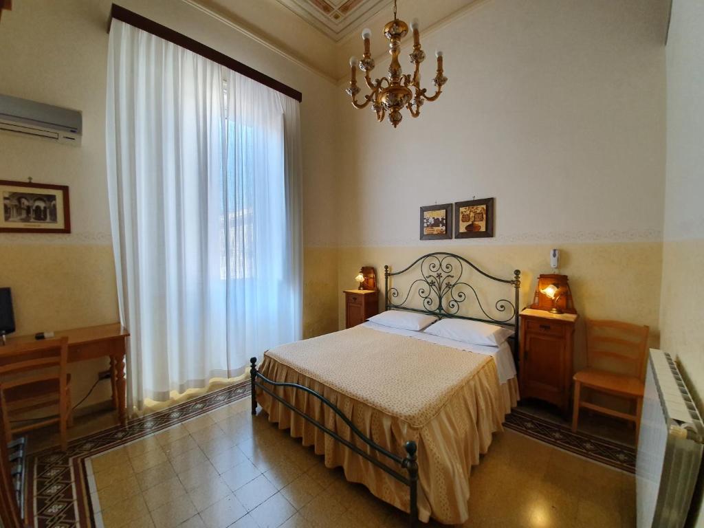 sypialnia z łóżkiem i żyrandolem w obiekcie Albergo Cavour w mieście Palermo