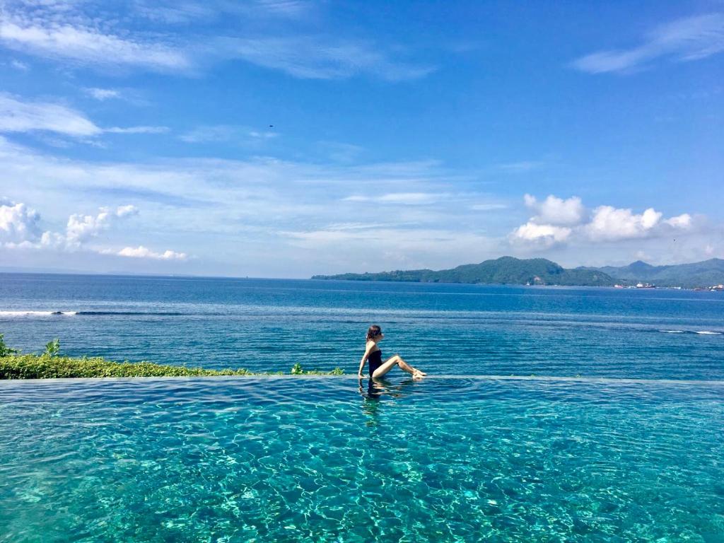 una mujer sentada en el agua en el océano en Luxury Villa Perla en Candidasa