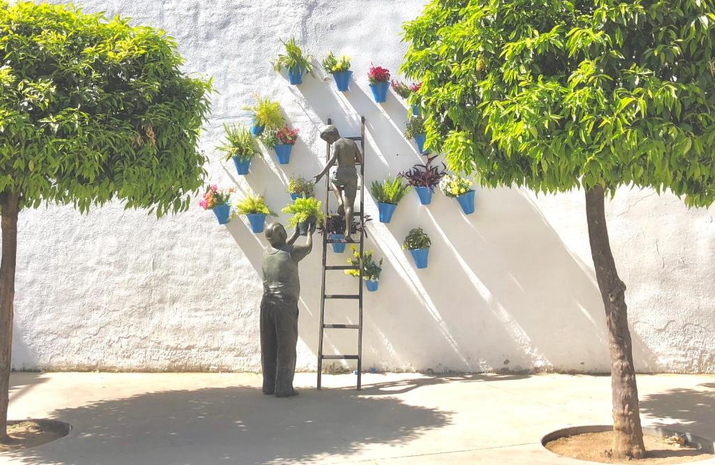 una estatua de dos personas alcanzando una escalera con plantas en El Encanto de Cordoba (Parking incluido), en Córdoba