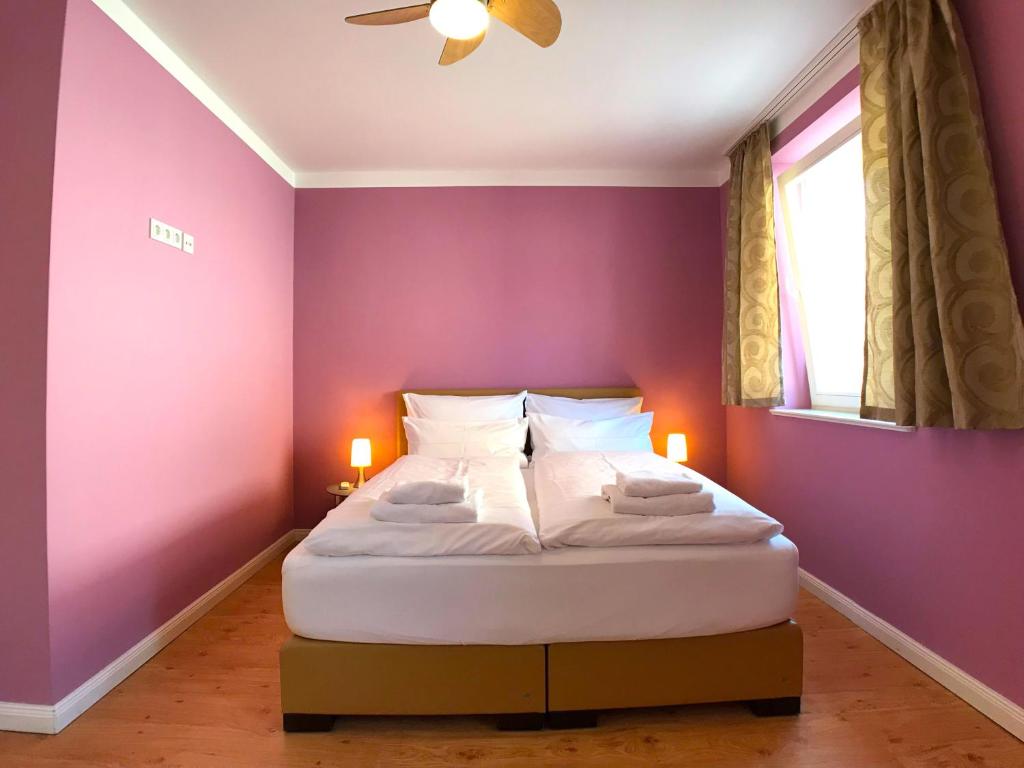 ein Schlafzimmer mit einem Bett mit lila Wänden und einem Fenster in der Unterkunft Amaroo - Apartments Potsdam “Holländisches Viertel” in Potsdam