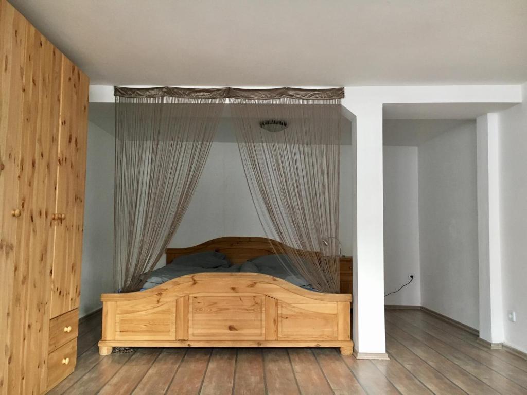 een slaapkamer met een houten bed en gordijnen bij Drei-Flüsse Ferienwohnung in Hannoversch Münden