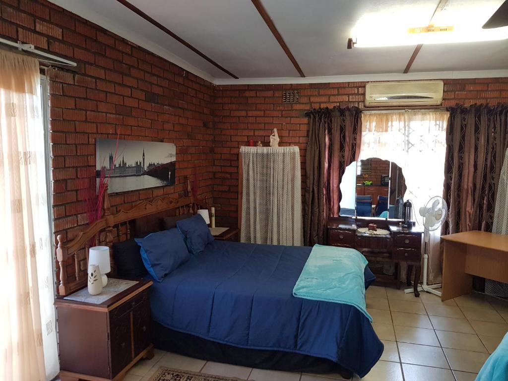 Un dormitorio con una cama azul y una pared de ladrillo en Cassiandra Place unit 2, en Richards Bay