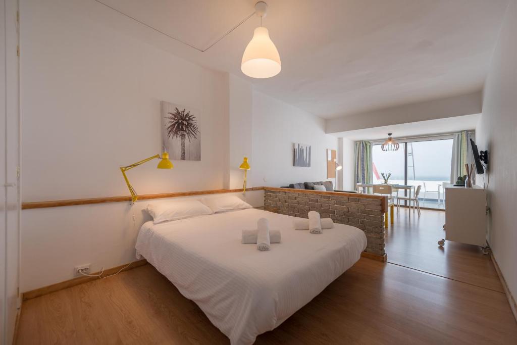 1 dormitorio con 1 cama blanca grande con 2 velas en Yellow Sun Marine I By CanariasGetaway, en Las Palmas de Gran Canaria
