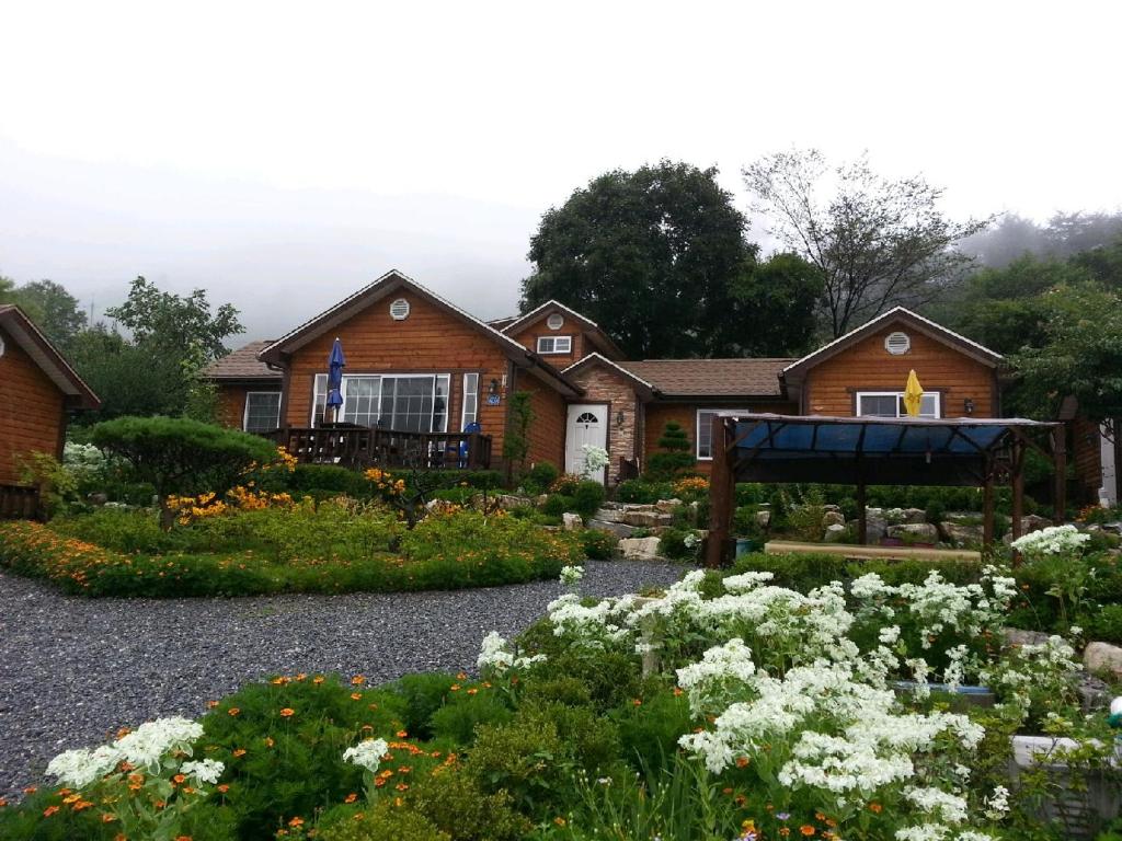 a house with a garden with flowers in front of it at Oraview Pension in Jeongseon