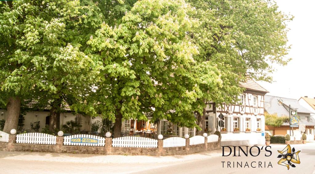 a fence with trees in front of a building at Dino's Trinacria in Friesenheim