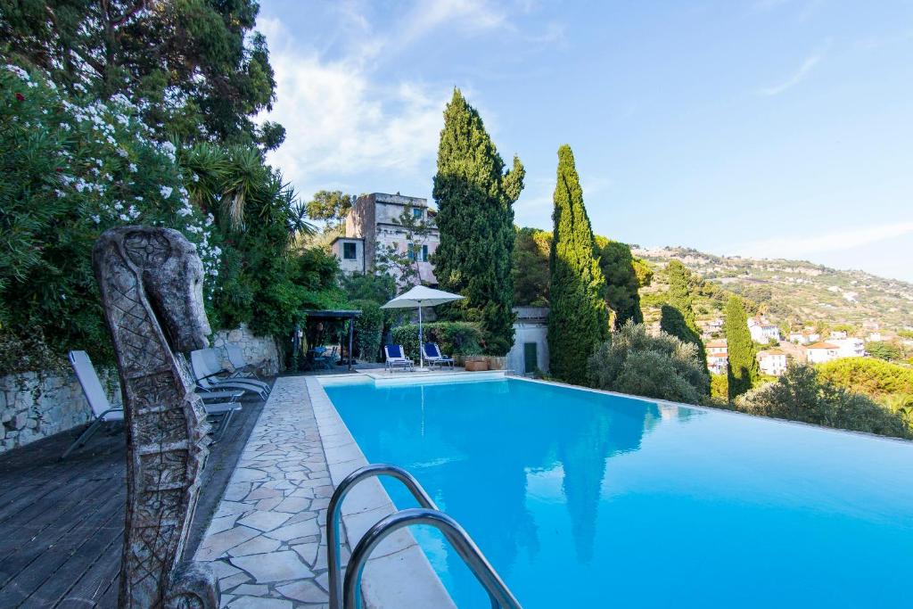 a blue swimming pool with chairs and trees at Villa Corinna in Ventimiglia