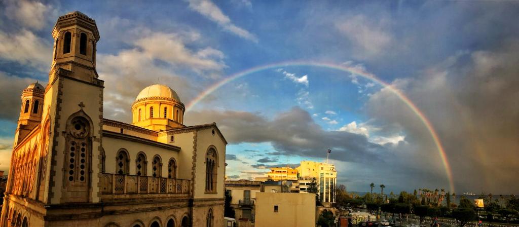 a rainbow in the sky over a building with a church at Studio in heart of Limassol in Limassol