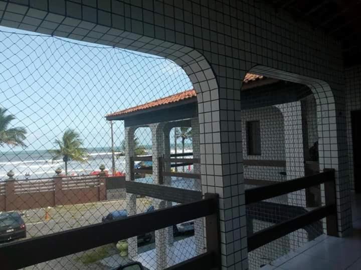 Pousada em Mongaguá Kali في مونغاغوا: اطلالة على شاطئ من مبنى به سياج