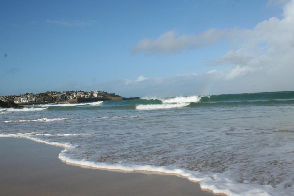 una spiaggia con un'onda nell'oceano di Rivendell Guest House a St Ives