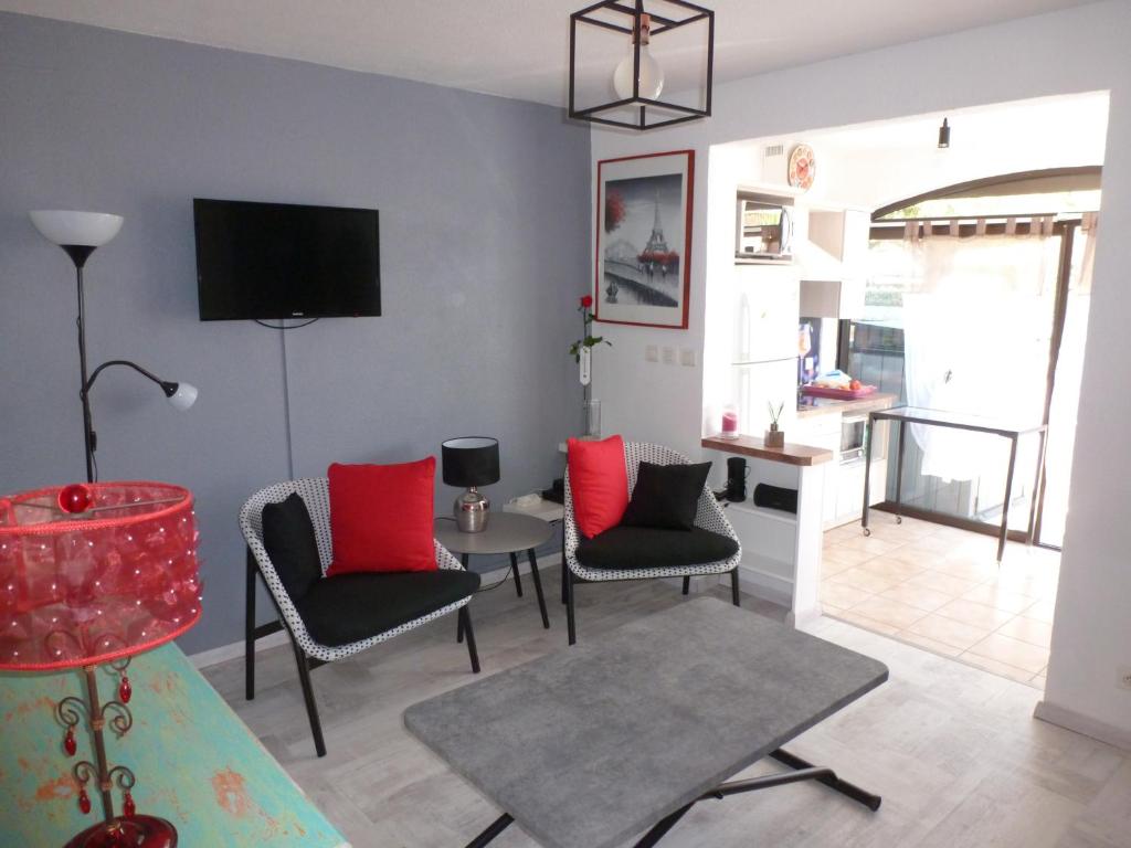 een woonkamer met stoelen, een tafel en een tv bij La Pergola de la Plage in Gruissan