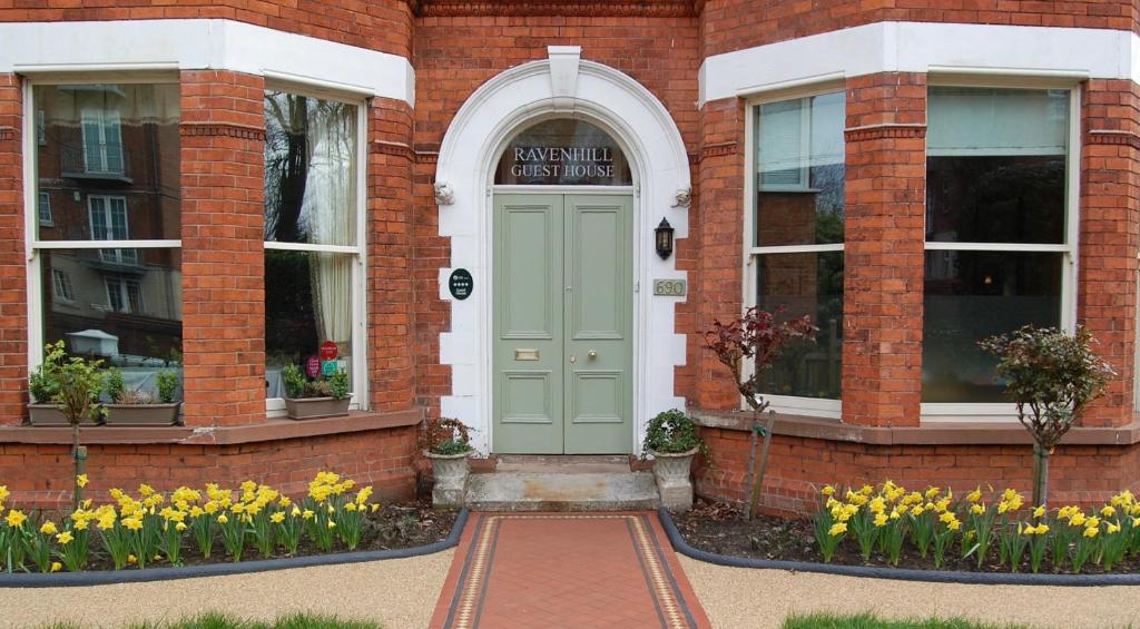 a brick building with a green door and flowers at Ravenhill House in Belfast
