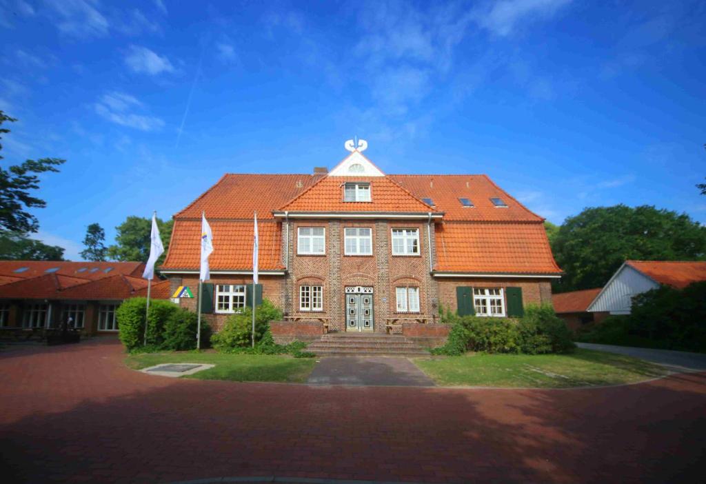 a large brick house with an orange roof at Jugendherberge Otterndorf in Otterndorf