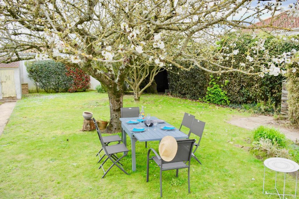 einen Tisch und Stühle in einem Garten mit einem Baum in der Unterkunft Coup de coeur assuré pour cette charmante maison à 400 m de la plage in Saint-Gilles-Croix-de-Vie