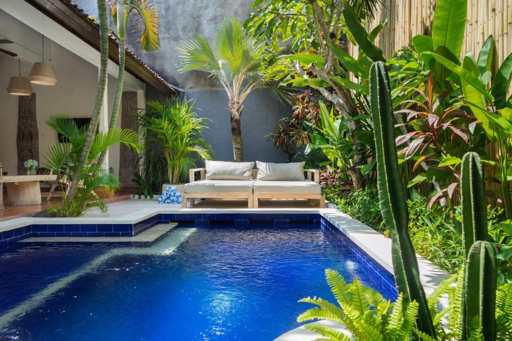 a pool in a garden with a couch and cactus at Smiling Cactus Villas - Seminyak in Seminyak