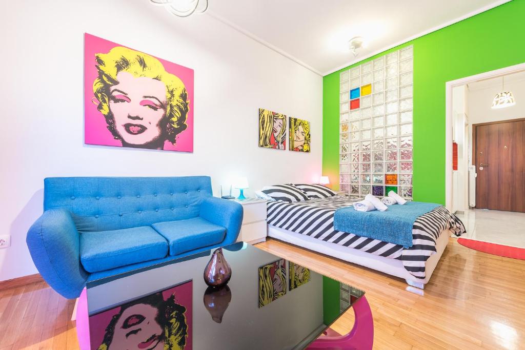 a living room with a blue couch and a bed at Zenios Amintas-Pop-artment for two in city center in Athens