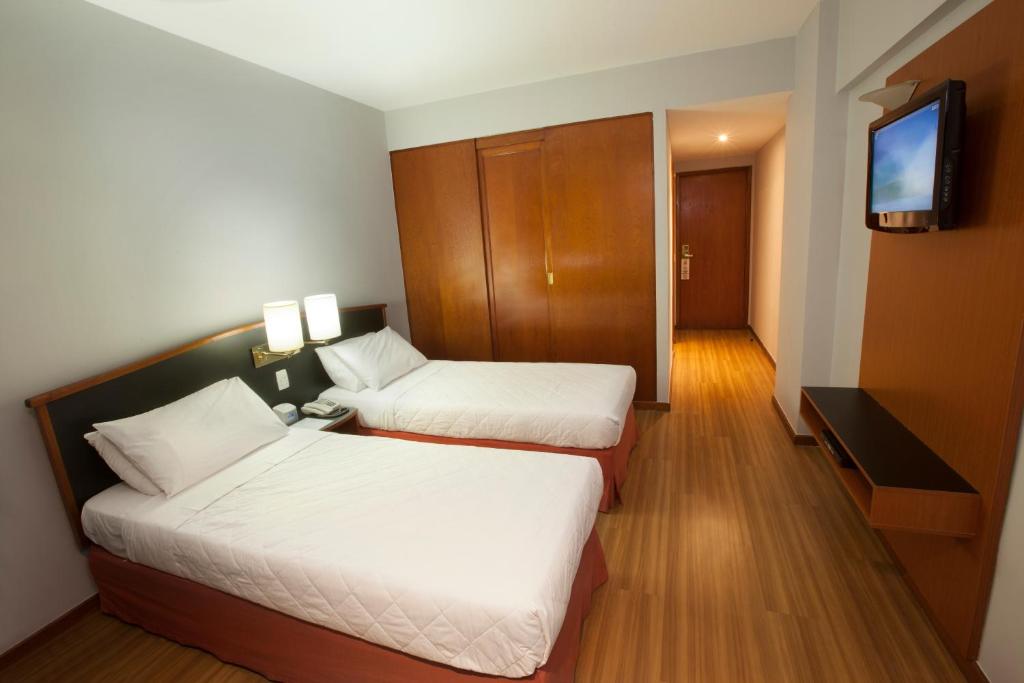 a hotel room with two beds and a television at Hotel Moncloa in São Paulo