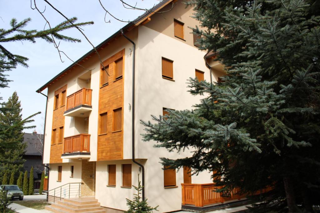 een gebouw met houten ramen en een boom bij Apartman Goca in Zlatibor