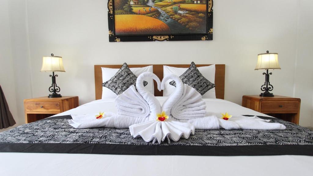 2 cigni sono seduti su un letto con asciugamani di Pondok Serayu ad Ubud