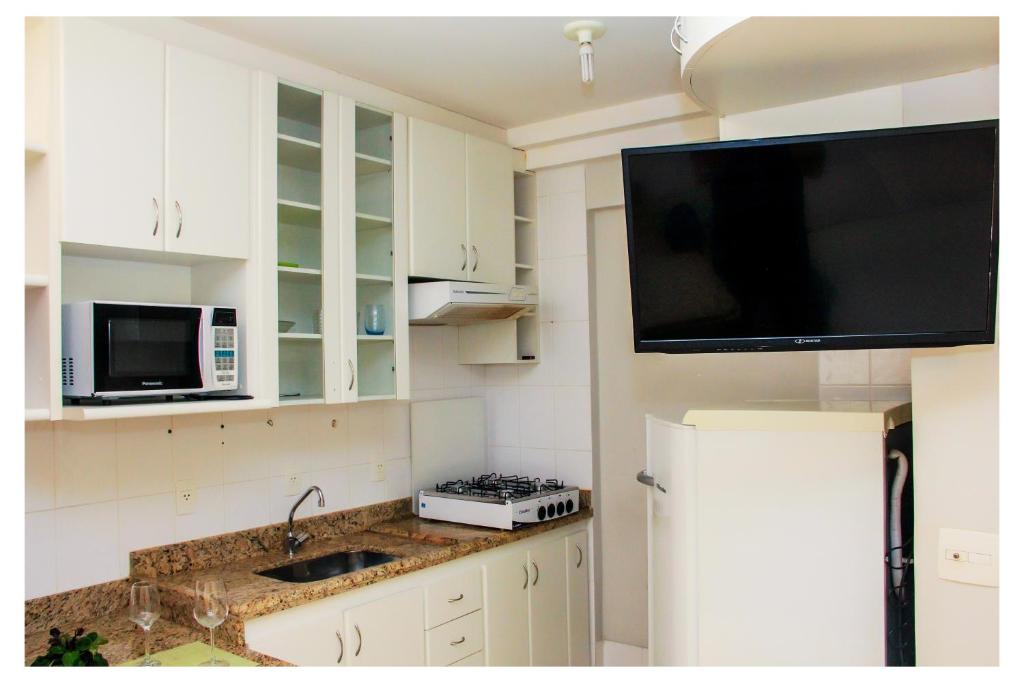 uma cozinha com um lavatório e uma televisão na parede em Flats Service Bueno em Goiânia