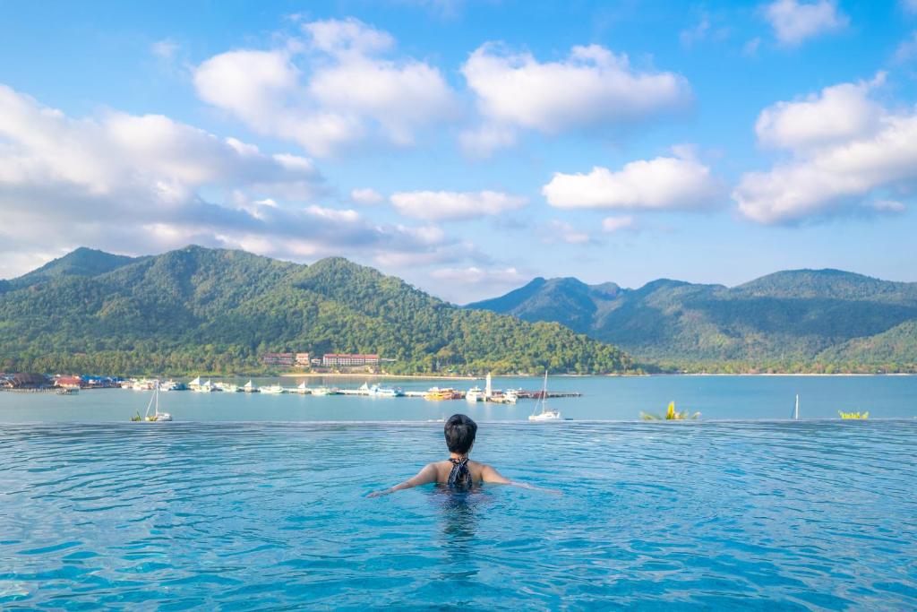 eine Person im Wasser mit Bergen im Hintergrund in der Unterkunft Bhuvarin Resort in Ko Chang