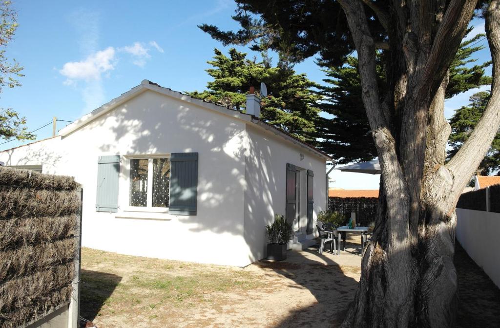 une maison blanche avec un arbre en face dans l&#39;établissement Charmante maison à 500 m du Remblais de Notre-Dame-de-Monts, à Notre-Dame-de-Monts