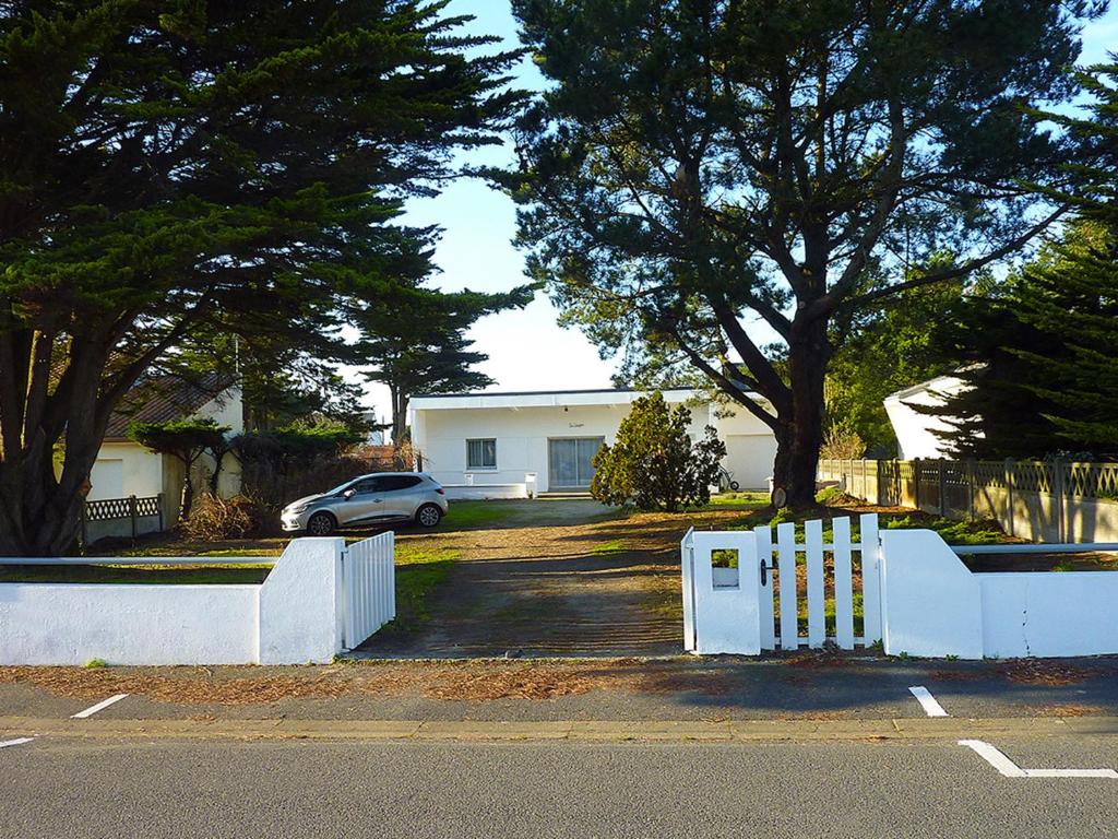 a white fence in front of a house with a car at Un style balnéaire moderne pour profiter de la mer in Pornichet