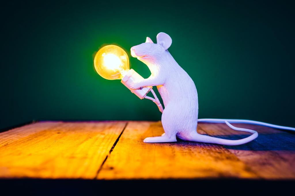 um brinquedo de rato branco segurando uma luz sobre uma mesa em PEPPIS LOFT em Merano