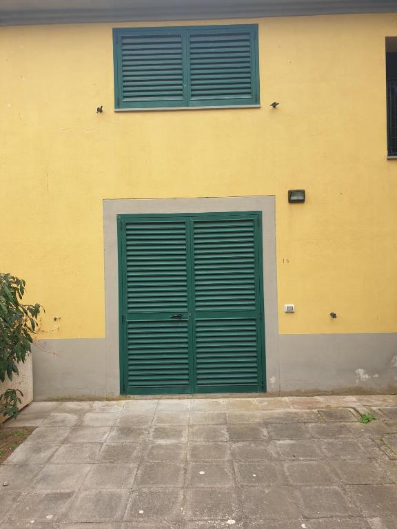 a green garage door and two windows on a building at Condominio Flabelli in Baratti