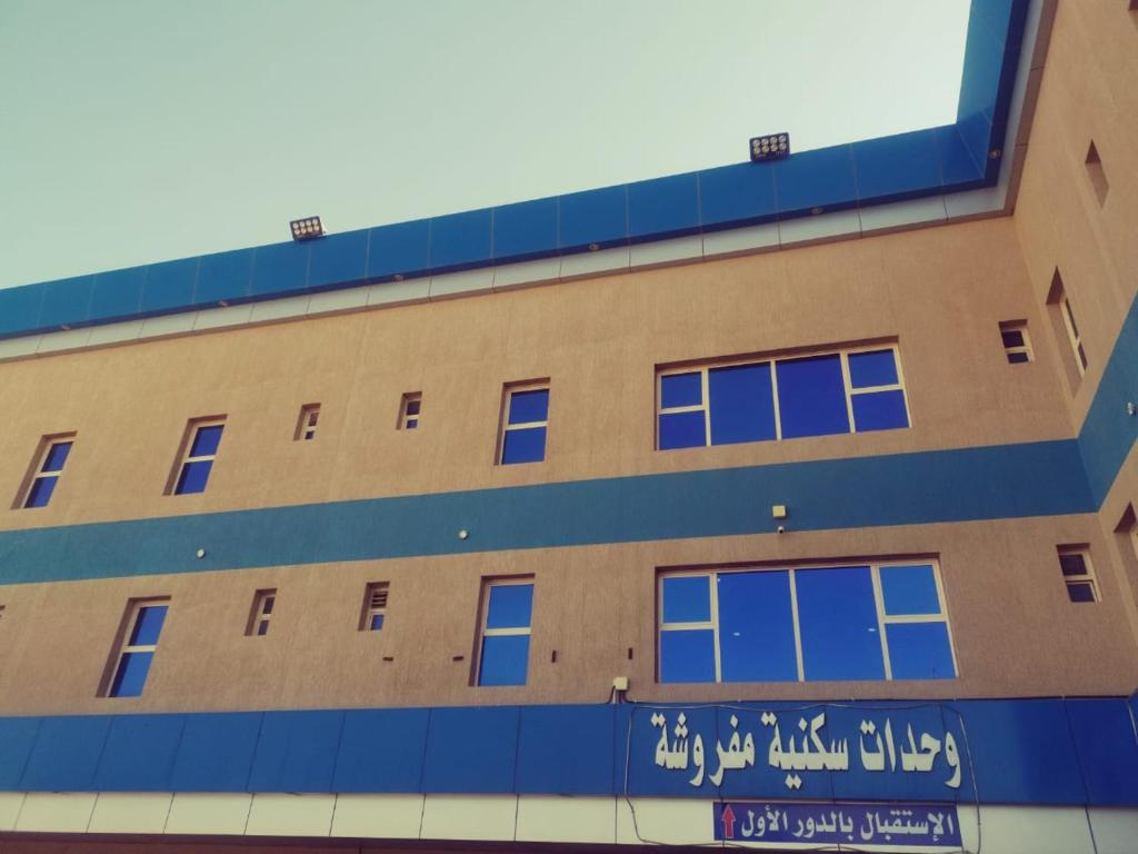 a building with blue windows and writing on the side at Sanabel Al Mish'an Furnished Units in Al Jithāmīyah