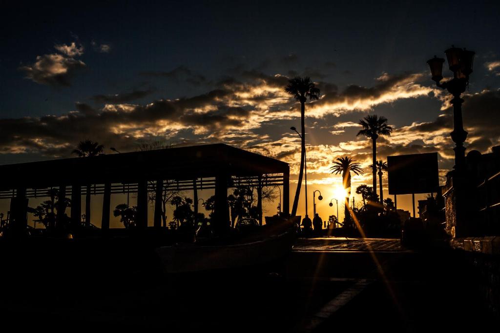 a sunset with palm trees and a building and the sun at TRAVEL STATION Bedandbreakfast in Bari