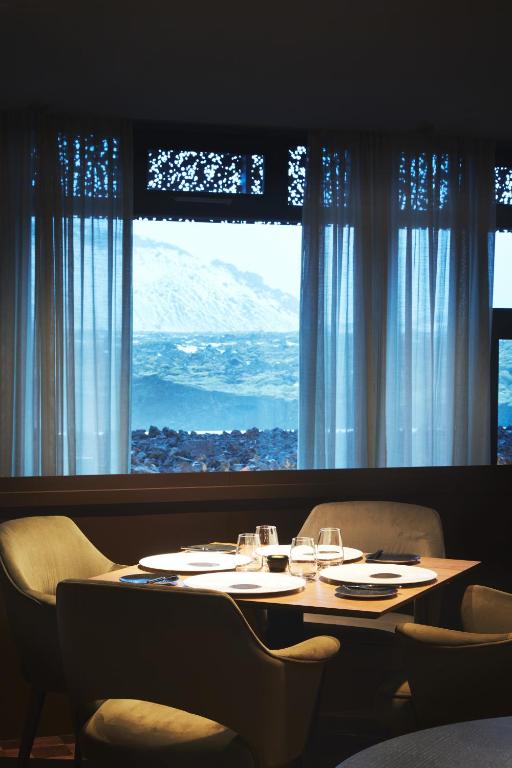 a dining room table with chairs and a large window at The Retreat at Blue Lagoon Iceland in Grindavík