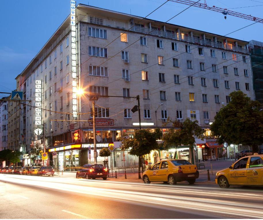 una calle de la ciudad con coches pasando por un gran edificio en Slavyanska Beseda Hotel, en Sofía