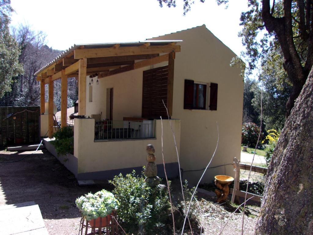 a small white house with a porch and a tree at a casetta di a Faragina in Zonza