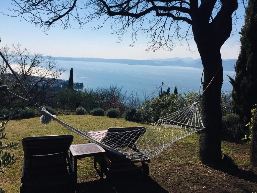 a hammock tied to a tree with a table and chairs at Casa Vacanze Mazurine10 in Torri del Benaco