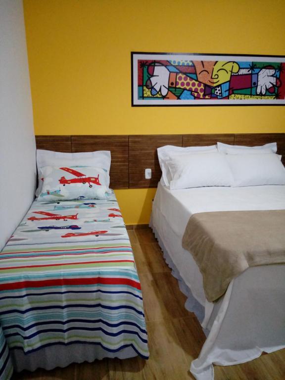una camera da letto con due letti e un dipinto sul muro di Flats Alegria a Olímpia