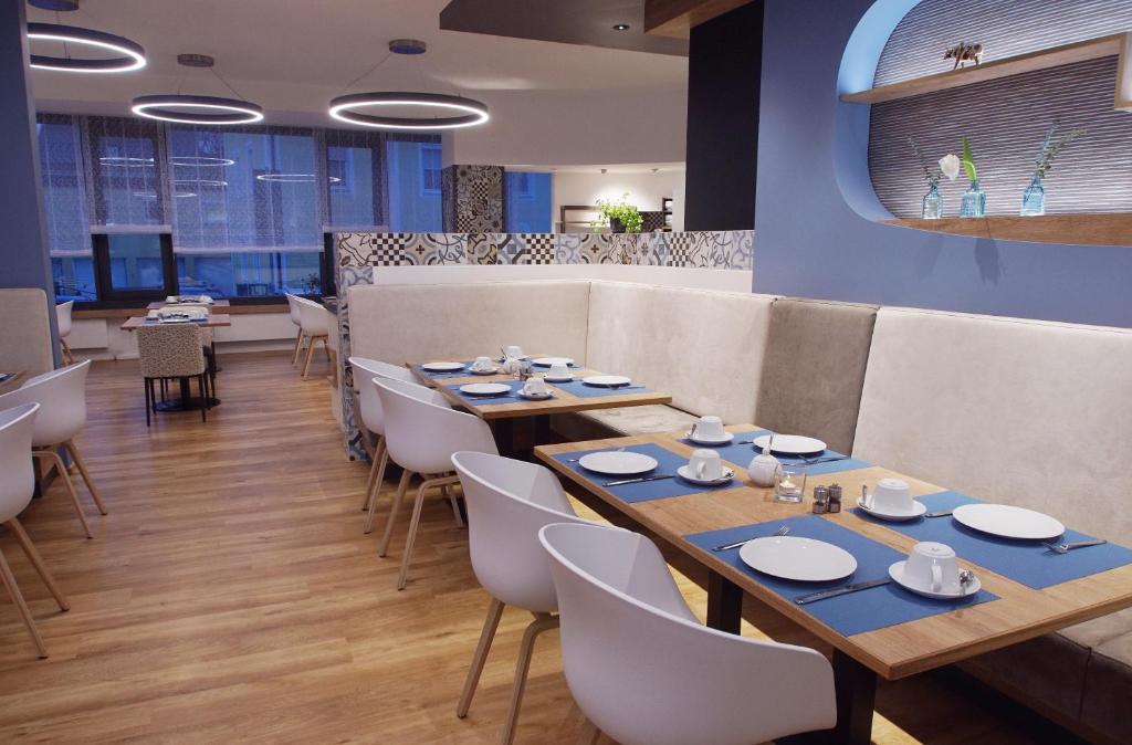 uma sala de jantar com mesas de madeira e cadeiras brancas em Hotel Peterhof - urban lifestyle Kempten em Kempten