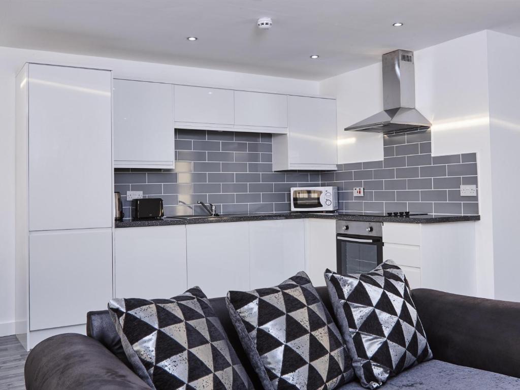 a kitchen with white cabinets and a couch at Fabrik: Winter Gardens Service Apartments 2 in Blackpool