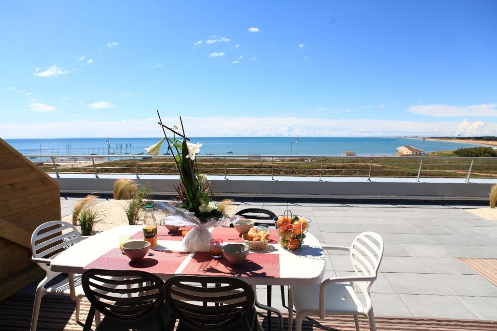 a table on a patio with a view of the ocean at Les Terrasses de l'Océan in Saint-Hilaire-de-Riez