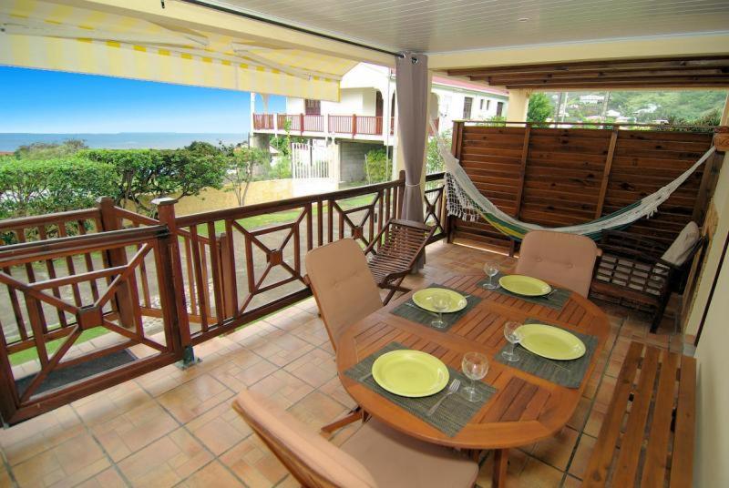 a wooden table and chairs on a balcony with a hammock at villa Prunier in Les Anses-dʼArlets