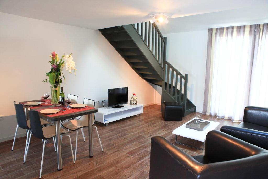 a living room with a table and a staircase at Les Terrasses de l'Océan in Saint-Hilaire-de-Riez