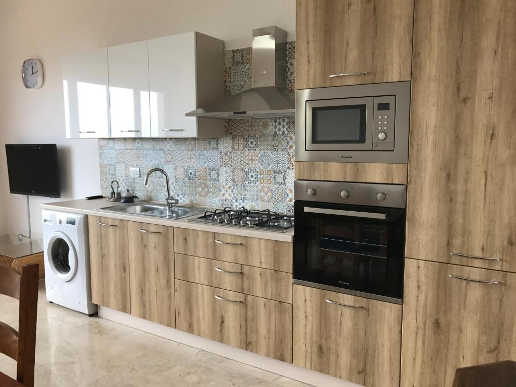 a kitchen with wooden cabinets and a microwave and a sink at Case Vacanze Zio Ciccio in Sciacca