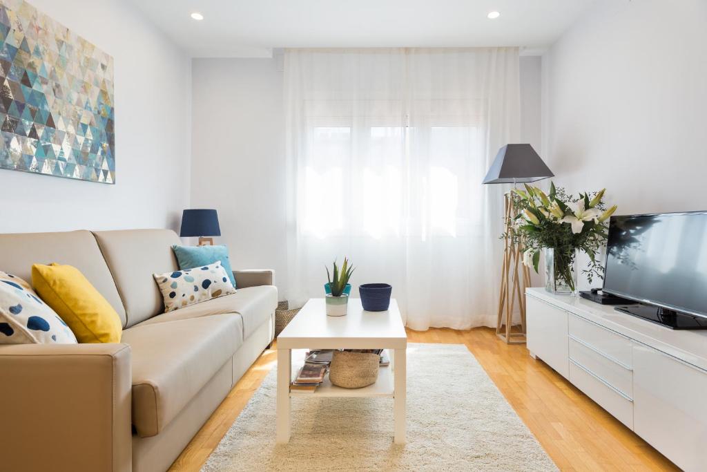 ein Wohnzimmer mit einem Sofa und einem TV in der Unterkunft Apartamento Rambla Catalunya in Barcelona