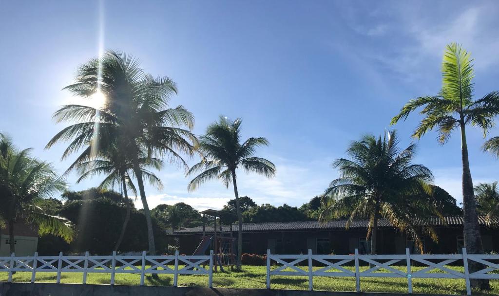 a group of palm trees and a white fence at Fazenda Bom Fim in Nísia Floresta