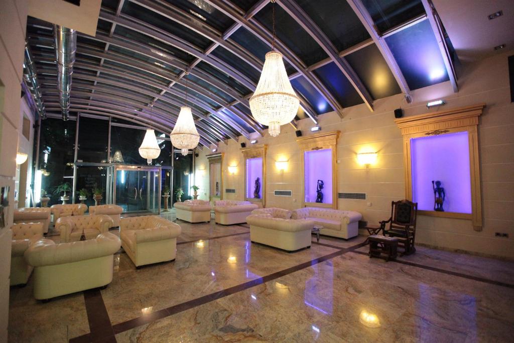Habitación grande con sofás blancos y lámparas de araña. en Hotel Astoria, en Igoumenitsa